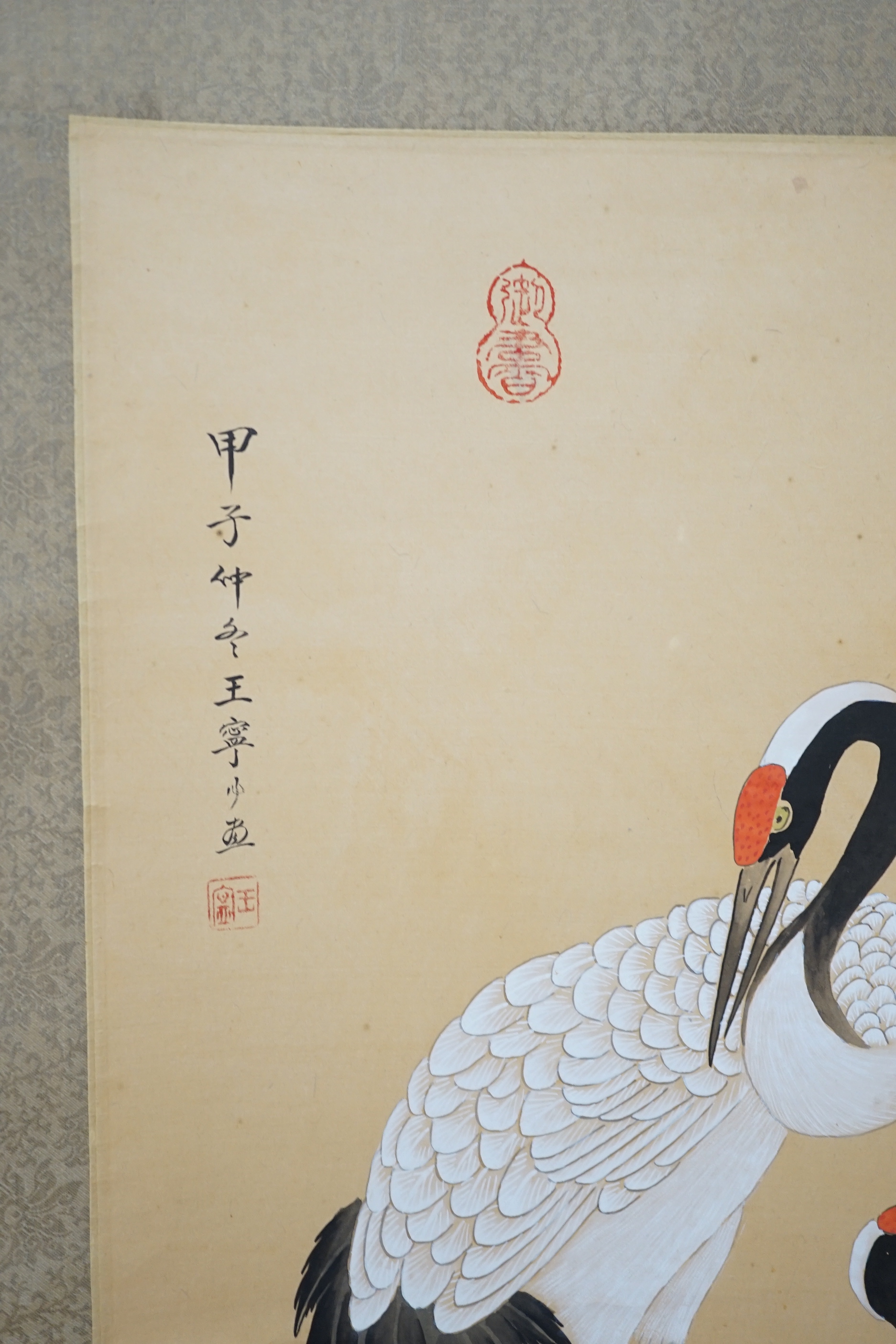 A 20th century Chinese hanging scroll watercolour on silk, two cranes on a pine tree, with brocade border, together with a blue Chinese silk table runner with brocade mon decoration